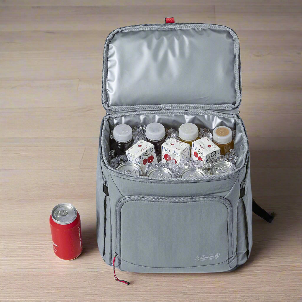 A Coleman 18-Can Soft-Sided Backpack Cooler in gray and red, featuring Temp-Lockâ„¢ insulation and a leakproof liner. The eco-friendly design includes padded straps, expandable side pockets for water bottles, and a front zipper pocket for valuables. Perfect for keeping drinks and snacks cool on outdoor adventures like picnics, camping, and beach trips.