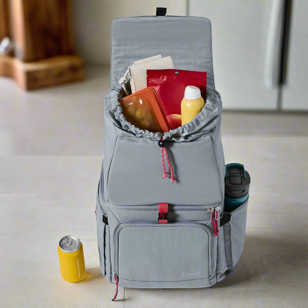 A Coleman 18-Can Soft-Sided Backpack Cooler in gray and red, featuring Temp-Lockâ„¢ insulation and a leakproof liner. The eco-friendly design includes padded straps, expandable side pockets for water bottles, and a front zipper pocket for valuables. Perfect for keeping drinks and snacks cool on outdoor adventures like picnics, camping, and beach trips.